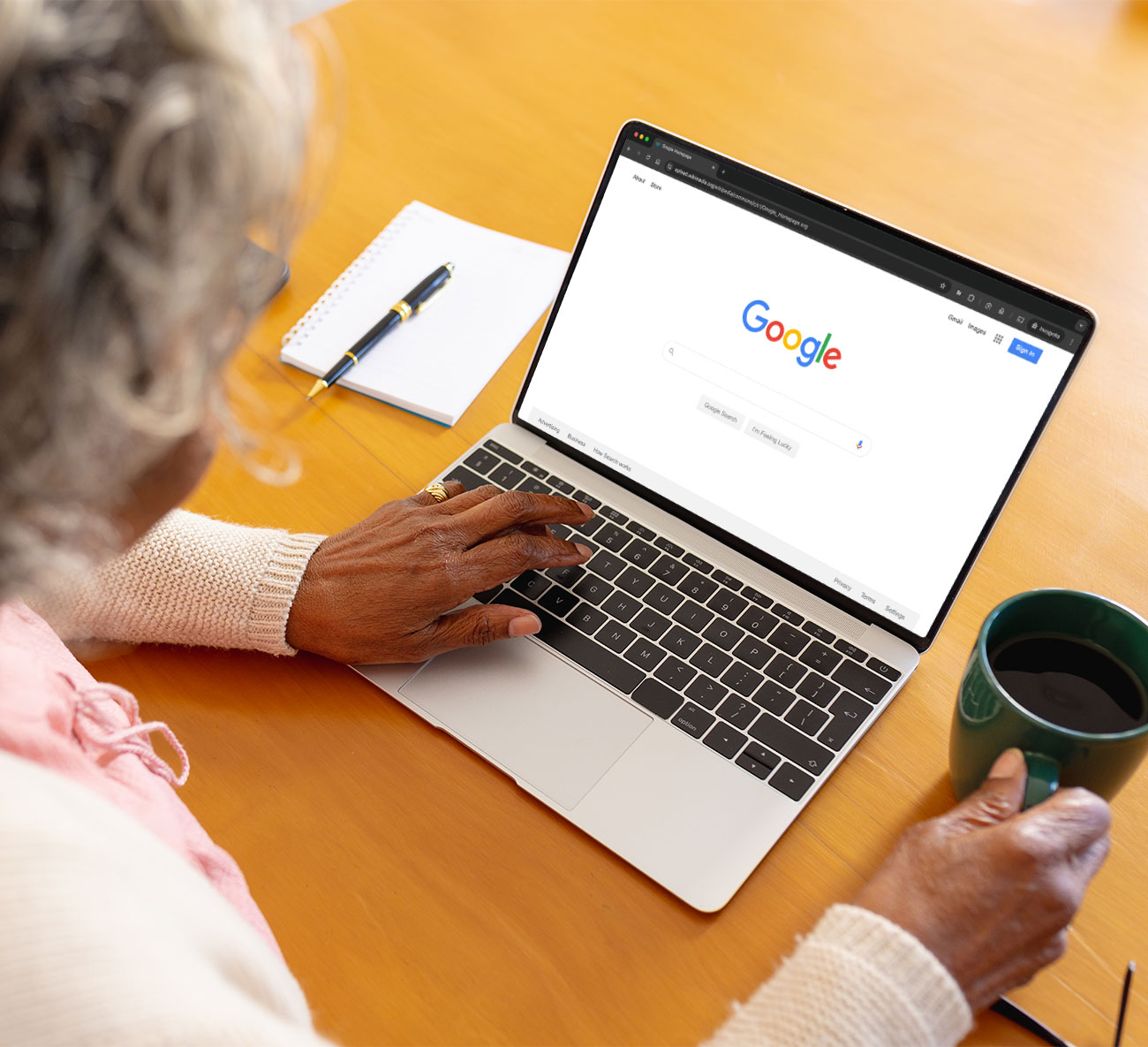 senior woman using her laptop and drinking coffee. Laptop screen is showing the Google homepage