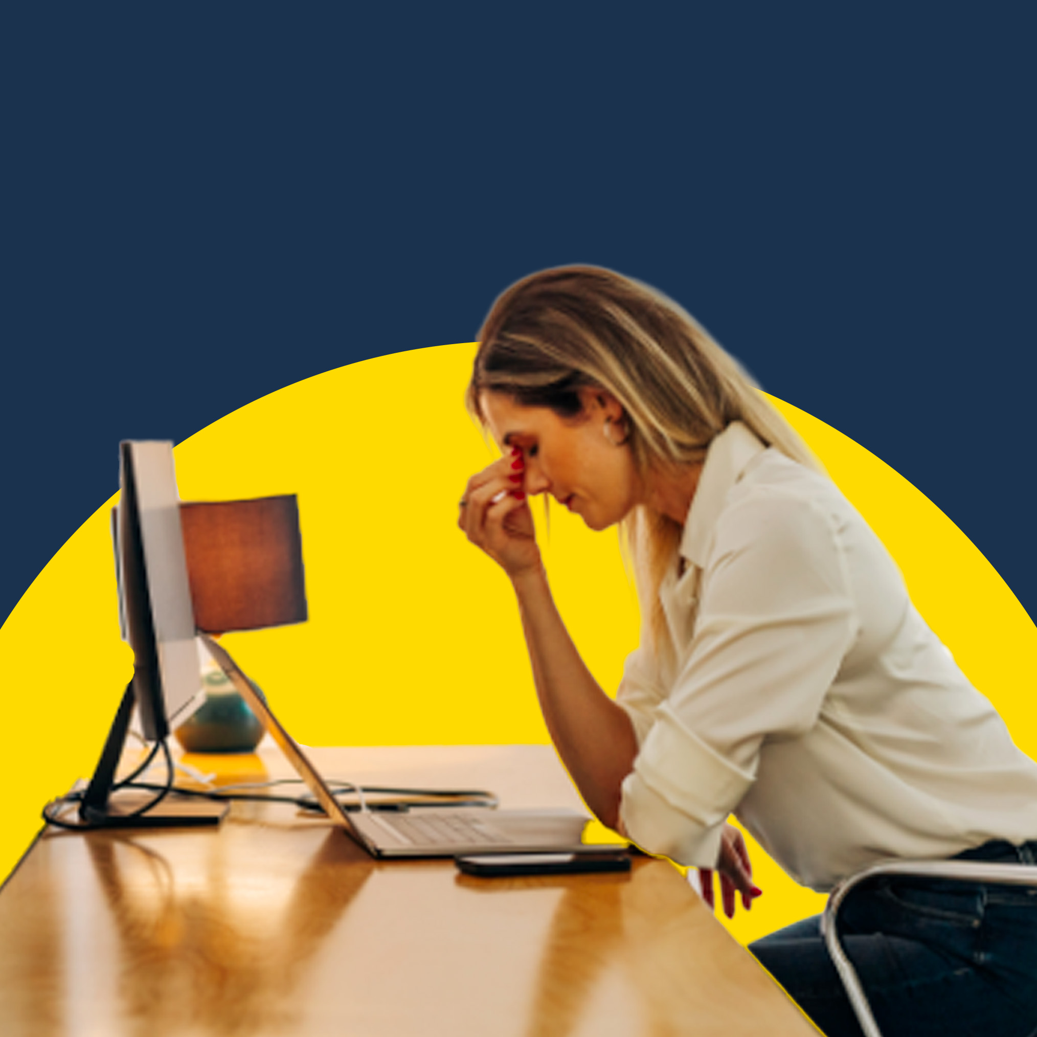 A woman working at a desktop computer with her head in her hands, looking stressed.
